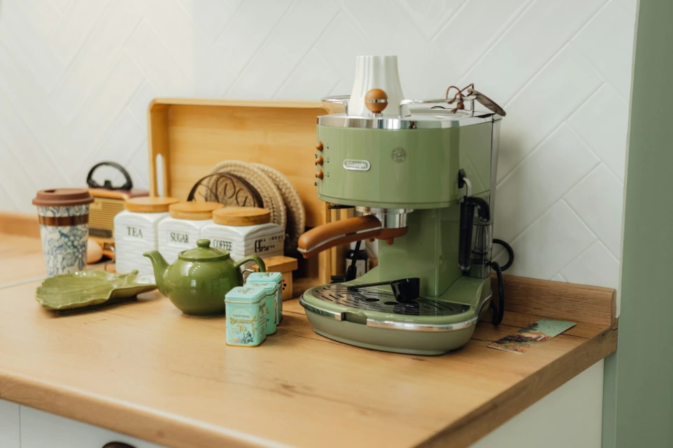A green coffee maker sitting on top of a wooden counter